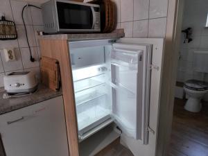 an open refrigerator with a microwave on top of it at Ferienwohnung Lux in Markische Heide