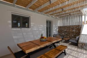 un patio con mesa de madera y bancos en Villa Cataleya 3 PRIVATE POOL, en Fanari