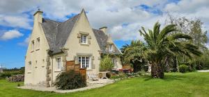 an old house with a palm tree in the yard at Chez Renée et Raynal B&B in Plounévez-Lochrist