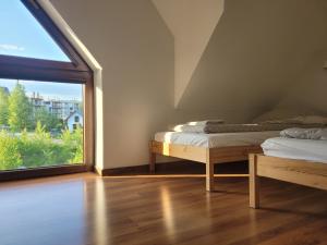 dwa łóżka w pokoju z dużym oknem w obiekcie Domki Pod Zamkami w Kluszkowcach