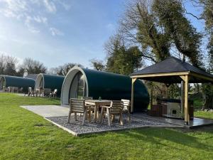 a table and chairs and a tent in a field at Kinelarty Luxury Glamping Pods Downpatrick in Downpatrick