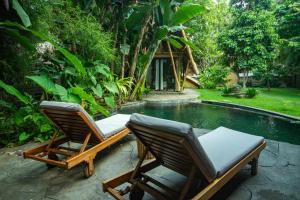 two chairs sitting next to a swimming pool at Cacao House Eco-Luxury Family Home by IBUKU near Green School Bali in Bringkit +52 photos