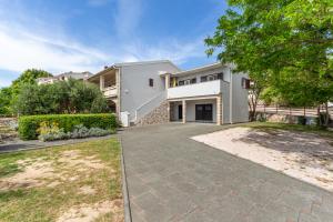 a large white house with a driveway at Apartments Luka in Pag