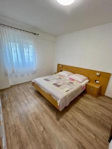 een slaapkamer met een bed en een houten vloer bij Apartmani Krunić in Barbat na Rabu