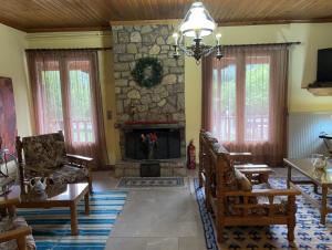 a living room with a stone fireplace and chairs at Guesthouse Sinoi in Vitina