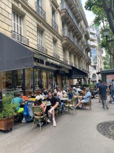un grupo de personas sentadas en mesas fuera de un edificio en Paris 16 Victor Hugo superbe studio, en París