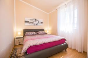 a bedroom with a bed with pink sheets and a window at Villa Michelle in Karojba