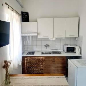eine Küche mit weißen Schränken, einer Spüle und einer Mikrowelle in der Unterkunft Apartments Ada in Rovinj