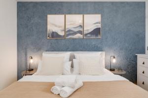 a bedroom with a white bed with three paintings on the wall at FENJOY Ferienapartments am Chiemsee - Balkon - BBQ in Bernau am Chiemsee