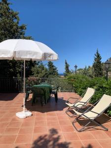 a patio with a table and chairs and an umbrella at Villa Maria in Castel di Tusa