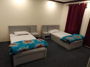 um quarto com duas camas e uma cortina vermelha em Ghanchi Inn Hotel em Dargai