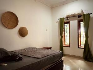 a bedroom with a bed and two windows at V & E Home Stay Cimaja Beach in Cimaja