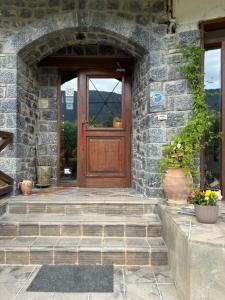 een stenen huis met een houten deur en een trap bij Guesthouse Sinoi in Vytina
