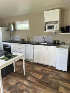 cocina con armarios blancos, fregadero y mesa en Tiny house max 4 people en Heberg