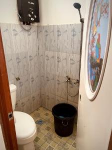 a bathroom with a toilet and a bucket at V & E Home Stay Cimaja Beach in Cimaja
