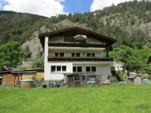 a house in a field in front of a mountain at Ferienhaus Schmid in Serfaus