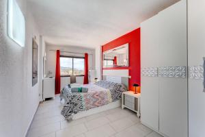 a bedroom with a bed and a red wall at 14th floor Sea View in Adeje +24 photos