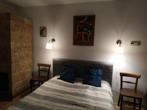a bedroom with a bed with blue pillows and two chairs at Dom pod Galazka in Bochnia