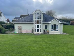 a white house with two chairs in a yard at Kilkenny rental The Folly Lodge minutes from city centre R95RYC8 in Kilkenny