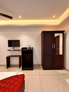 a room with a bed and a desk with a television at Luxe Hotel Thekkady in Thekkady