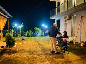 Ein Mann steht neben einem Tisch mit einem Kind, das einen Drachen fliegt. in der Unterkunft Family Hotel Sunset in Chakvi