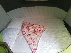 Una cama blanca con una manta con flores. en Trijų žvaigždučių palapinė Vilniuje en Vilna