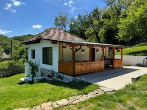a small white house with a large deck at Casa rustica Cerdacul Batranesc in Urlueşti