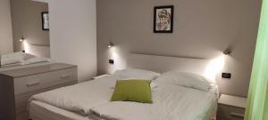 um quarto com uma cama branca e uma almofada verde em Appartamento Alba em Folgaria