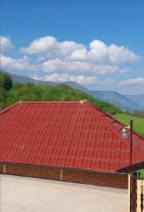 ein rotes Dach auf einem Gebäude mit Bergen im Hintergrund in der Unterkunft Kuća za odmor Andrea in Bajina Bašta