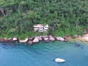 una vista aerea di una casa su un'isola rocciosa in acqua di Vila Pedra Mar a Praia Vermelha