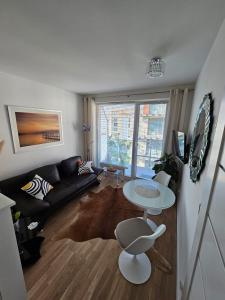 a living room with a black couch and a table at Apartament Sundown Regina in Kołobrzeg