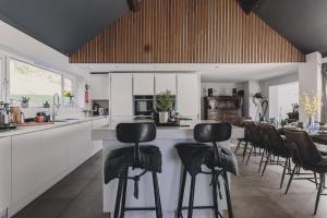 a kitchen with a bar with chairs around it at The Curlews - Waterside, boutique home with 360 panoramic views and 10 person Hyool, Teignmouth in Bishopsteignton