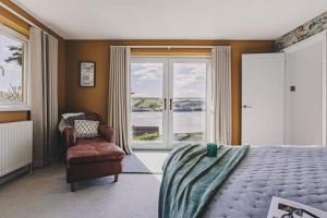 a bedroom with a bed and a chair and a window at The Curlews - Waterside, boutique home with 360 panoramic views and 10 person Hyool, Teignmouth in Bishopsteignton