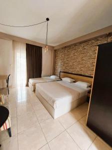 a bedroom with two beds and a brick wall at Villa Nickolas in Paleo Tsifliki