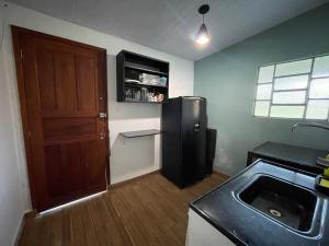 uma cozinha com um frigorífico preto e um lavatório em Viva momentos únicos com quem você realmente gosta em Juiz de Fora