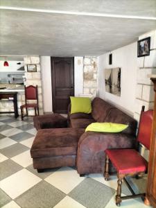 ein Wohnzimmer mit einem braunen Sofa und Stühlen in der Unterkunft Charmant appart avec extérieur in Aigues-Mortes