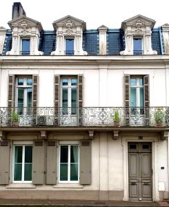een wit gebouw met ramen en een balkon bij La Maison VH in Mont-de-Marsan