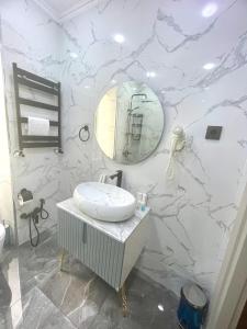 een witte badkamer met een wastafel en een spiegel bij Perla De Mar Hotel in Baku