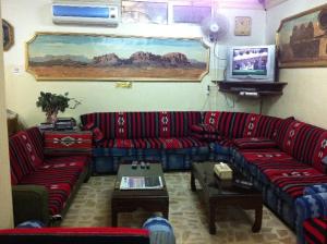 a living room with red couches and a tv at Farah Hotel in Amman