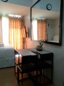 1 dormitorio con escritorio, espejo y cama en Delta Charlie Staycation CDO, en Cagayan de Oro