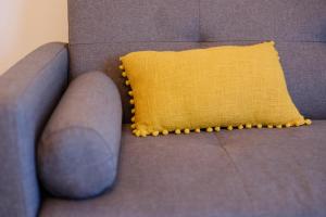ein gelbes Kissen auf einer grauen Couch in der Unterkunft VEryNICE - New Cozy Family Apartment near Venezia Mestre in Mestre
