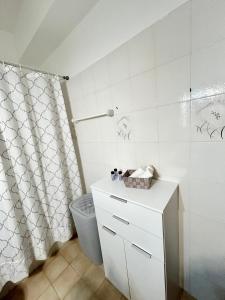een badkamer met een douchegordijn en een witte kast bij Philoxenia House in Asklipio in Asklipiḯon