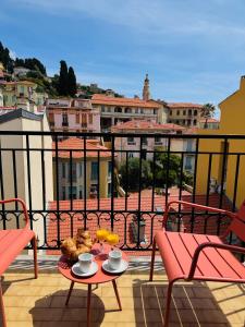 un balcón con una mesa con un plato de comida. en Hôtel Narev's, en Menton