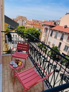 two pink chairs and a table on a balcony at Hôtel Narev's in Menton