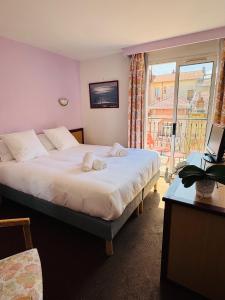 sypialnia z łóżkiem i dużym oknem w obiekcie Hôtel Narev's w Mentonie