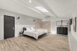 a white bedroom with a bed and a bathroom at Villa Rose - Padel - Piscine - Cinéma & Poker Room in Saint-Jory