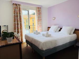 sypialnia z dużym białym łóżkiem i oknem w obiekcie Hôtel Narev's w Mentonie