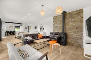 a living room with leather furniture and a brick wall at Villa Rose - Padel - Piscine - Cinéma & Poker Room in Saint-Jory