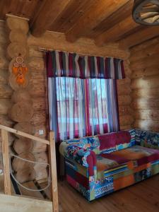 um quarto com uma cama e uma janela num chalé de madeira em Smuku Muiža em Remte