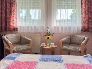 a bedroom with two chairs and a bed and a table at Hotel DenRiKo in Heidelberg